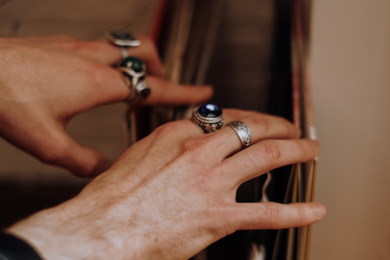 Two hands going through a file with multiple gemstone and sterling silver fashion rings on