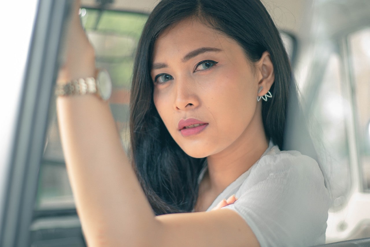 A woman in a car wearing a mixed metal watch and a set of earrings