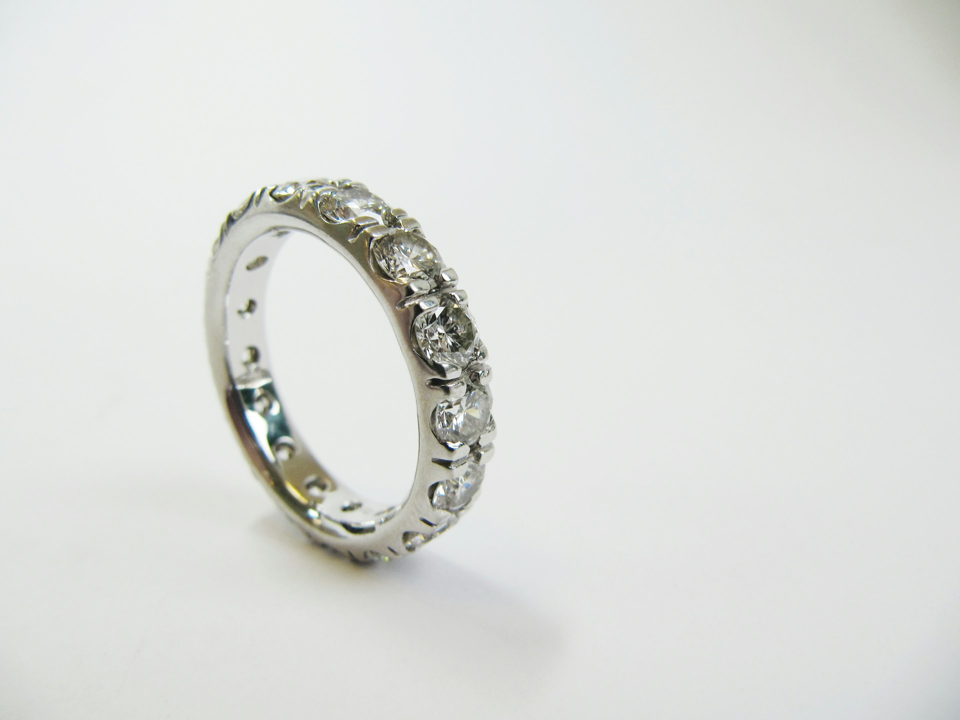 a platinum diamond wedding band on a white surface
