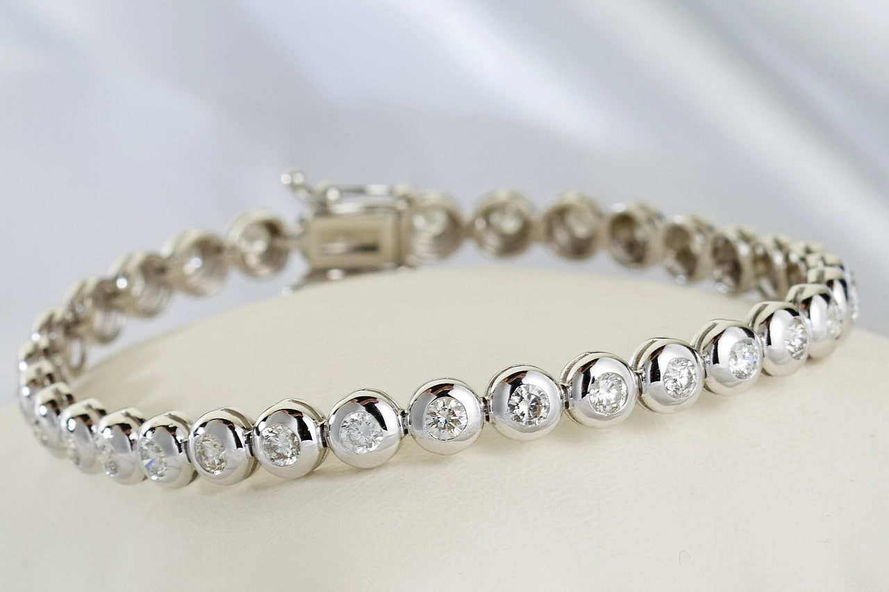 a platinum diamond tennis bracelet on a white surface