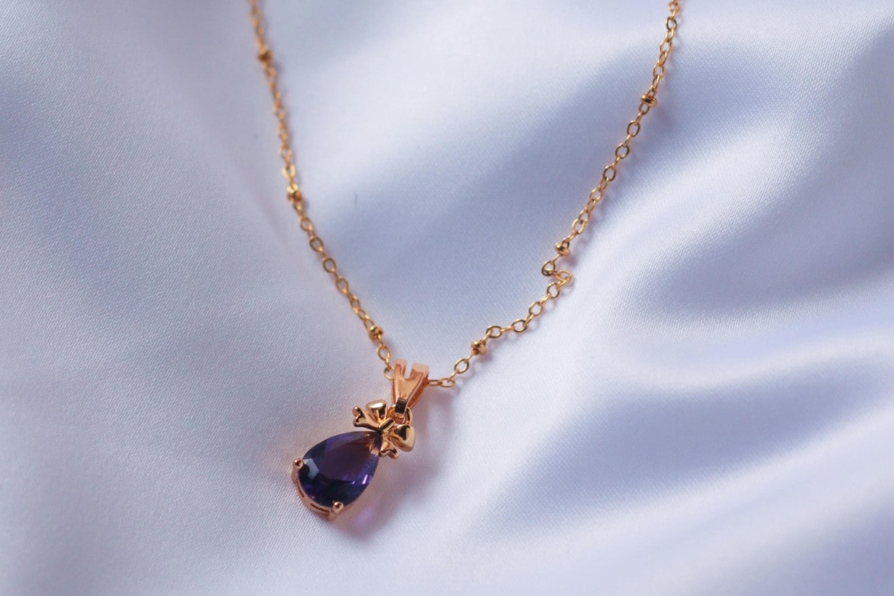 a rose gold pendant necklace featuring a pear shape amethyst