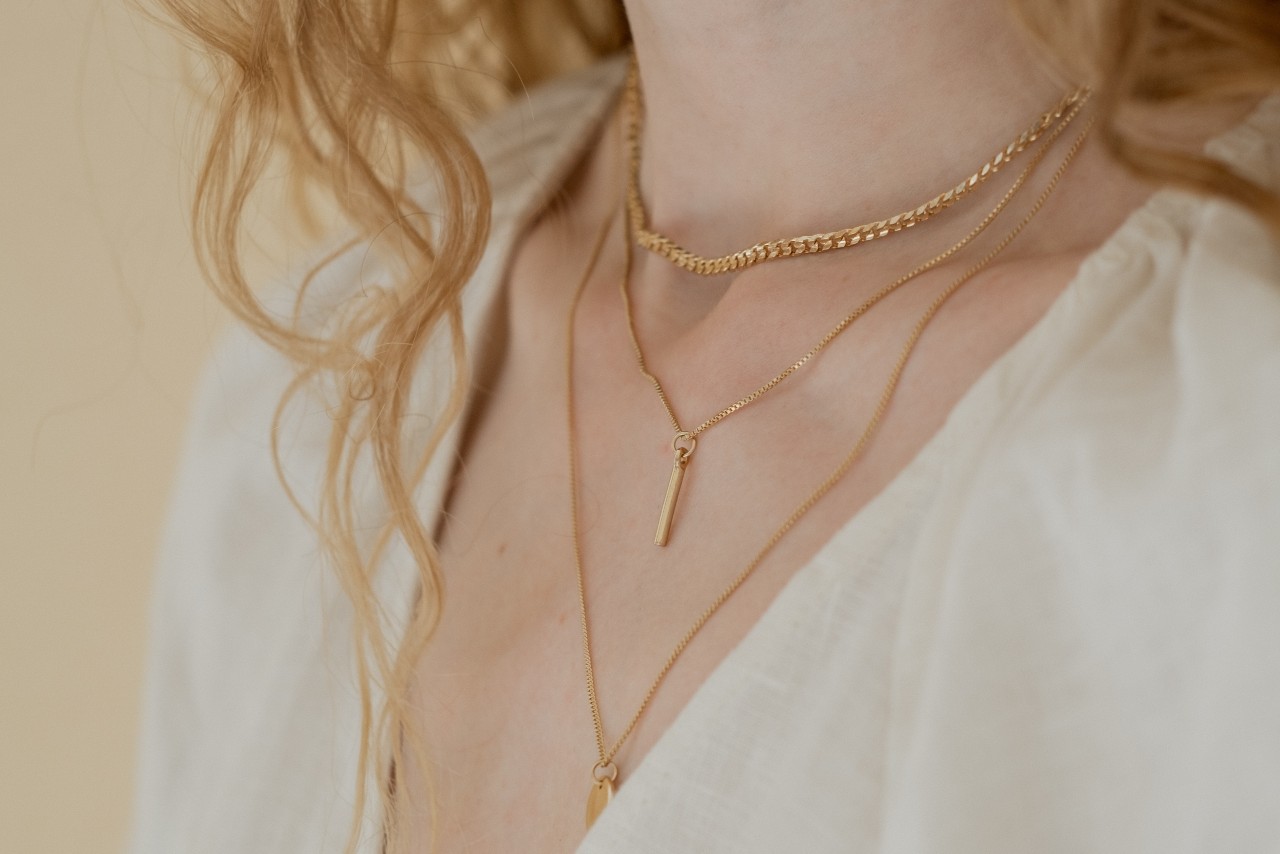 close up image of a woman’s neckline adorned with three layered yellow gold necklaces