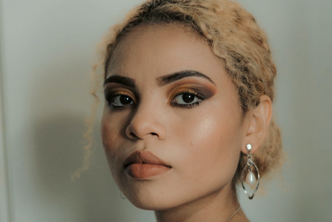 a woman looking into the camera wearing a unique pair of silver and pearl earrings