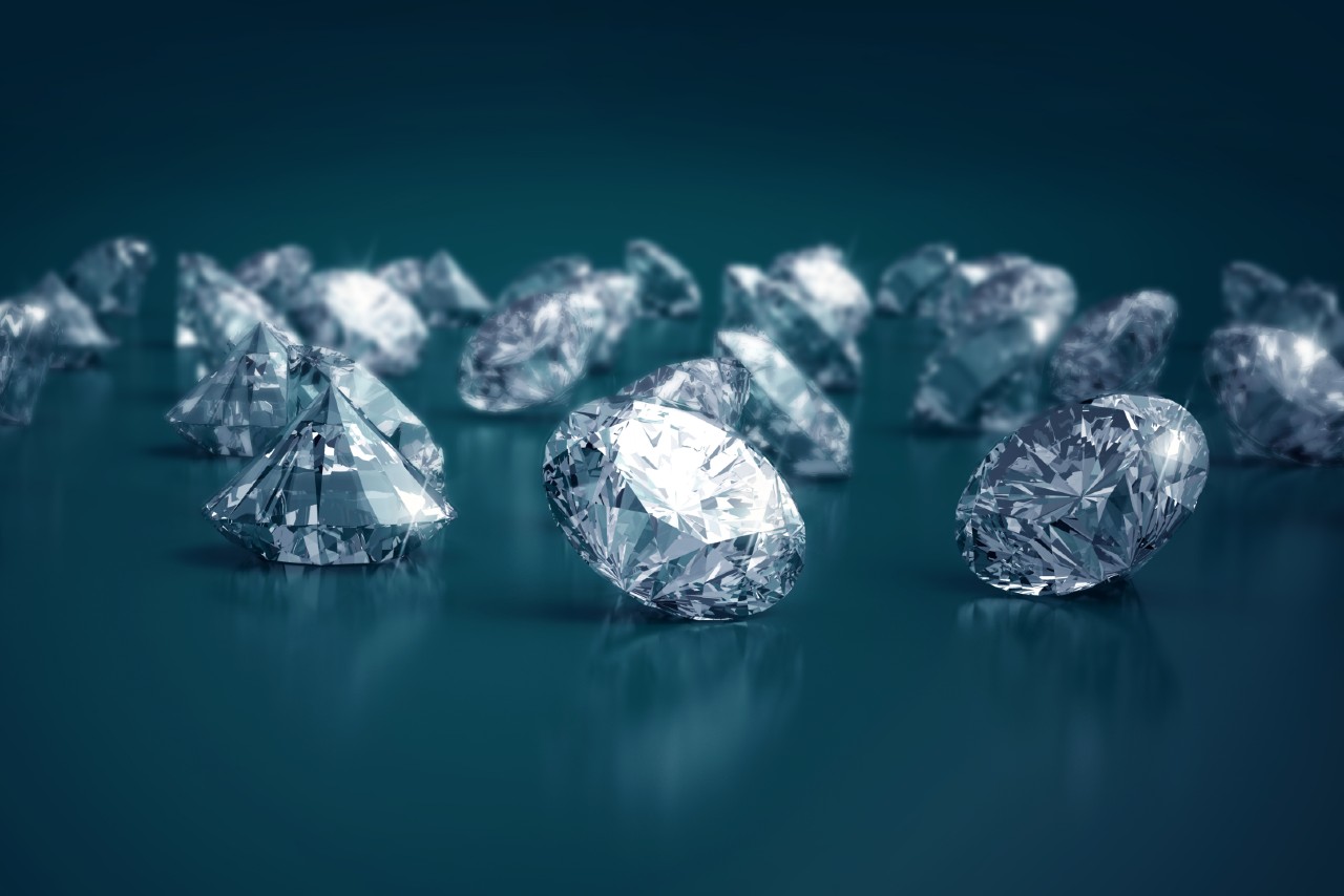 A selection of round cut diamonds on a dark blue-gray surface.