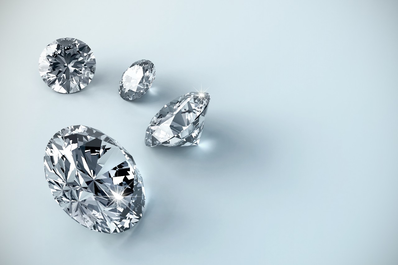 Four round cut diamonds of various sizes on a gray surface.