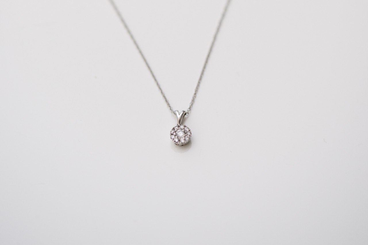 A close-up of a delicate diamond pendant necklace on a white background.