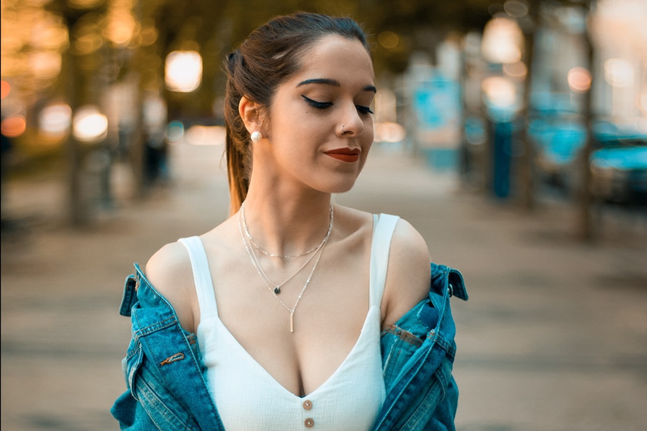 A casually dressed young woman wearing three delicate layered necklaces.